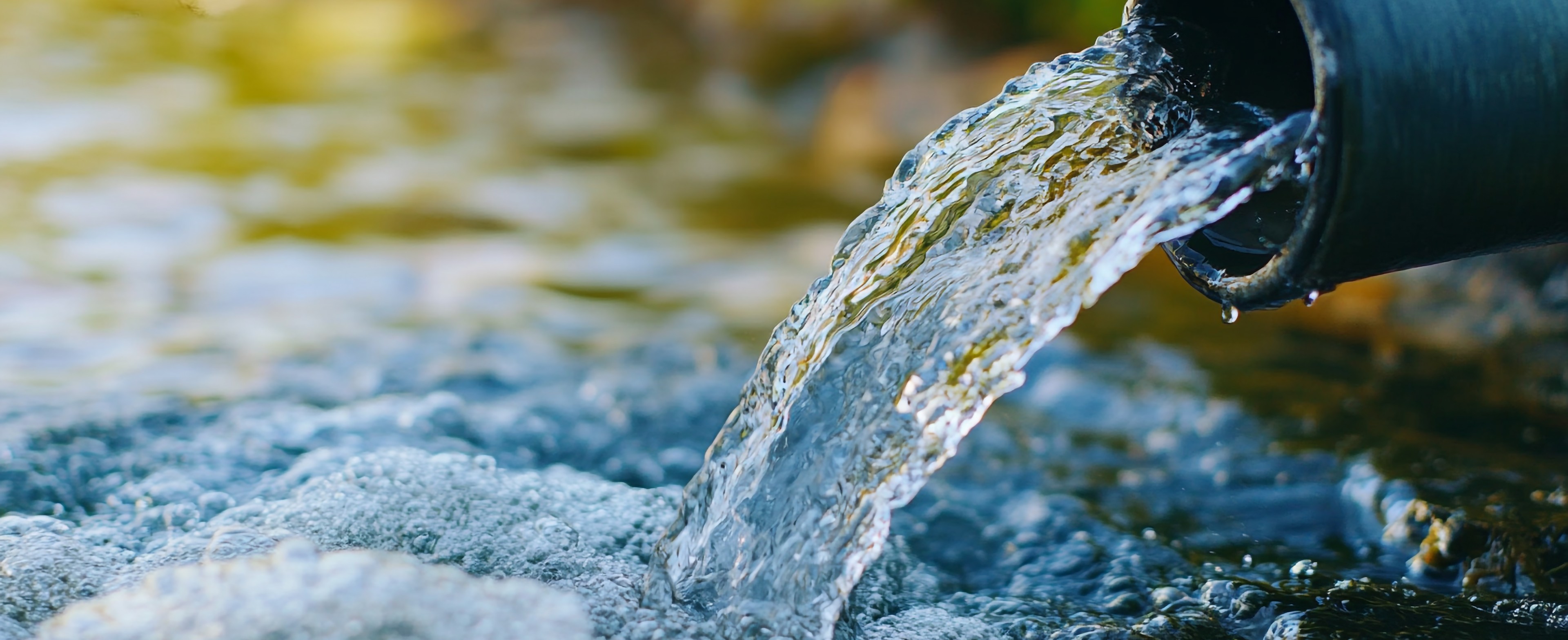 Treated water discharging from an outflow pipe into a stream.